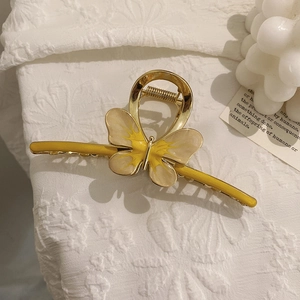 Close-up of golden metal butterfly hair claw clip with yellow resin and crystal details