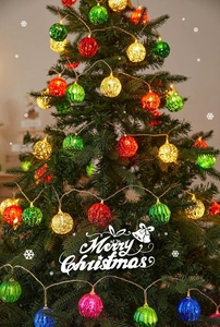 Close-up of colorful glowing hollow LED ball lights on a decorated Christmas tree