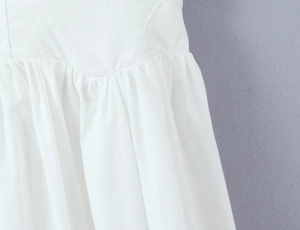 Detailed view of the white cotton dress featuring elegant ruched waist and pleated fabric