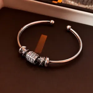 Silver open bangle with zircon pavé cylinder and star pendant on brown backdrop