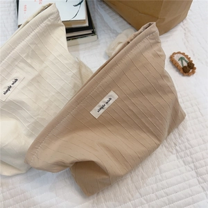 Detail of striped cotton pouch bags in beige and camel with simple wish fabric label