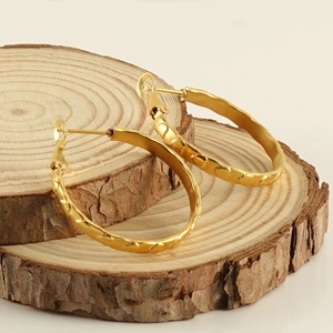 Goldene runde Creolen mit Wellentextur auf natürlichen Holzblöcken präsentiert