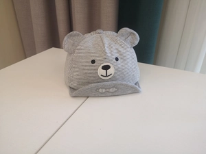 Detailed view of striped cotton baby hat featuring cute bear ears and facial embroidery
