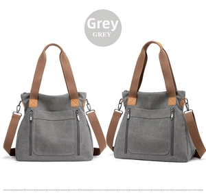 Detail view of grey canvas tote with brown straps and dual front vertical zippers
