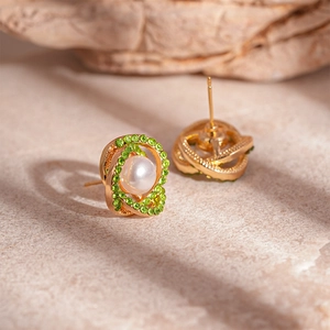 Macro shot of gold-plated hoop earrings with green rhinestones and white pearls