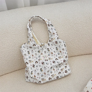 Close-up of white quilted tote bag featuring colorful cartoon patterns and woven label
