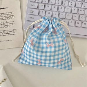 Detailed view of blue checkered drawstring pouch with pink bow prints and cotton ropes
