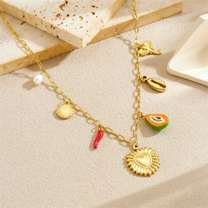 Gold chain necklace with pearl shell red chili and papaya pendants on a stone surface