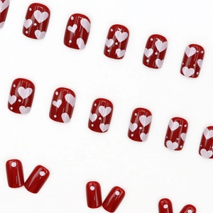 Glossy cherry red press-on nails set featuring white heart and polka dot patterns