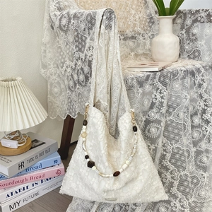 Détail du sac à fleurs blanches avec bandoulière en perles et étiquette tissée
