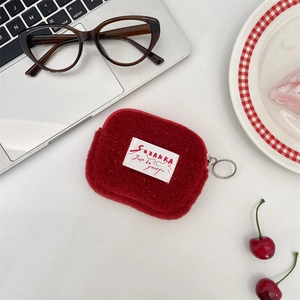 Detailed view of a small red plush square coin purse pouch on a white desk surface