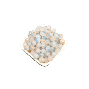 Macro shot of 8mm two-tone gradient glass beads with blue and orange spots in a bowl