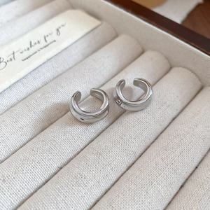 Close-up of polished silver geometric ear cuffs placed in a soft beige velvet jewelry box