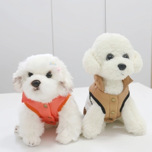 Dettaglio di gilet invernali per cani in arancione e kaki su piccoli cani bianchi