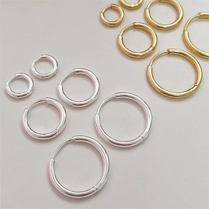 Flat lay of multiple sizes 925 sterling silver hoop earrings in gold and silver finishes