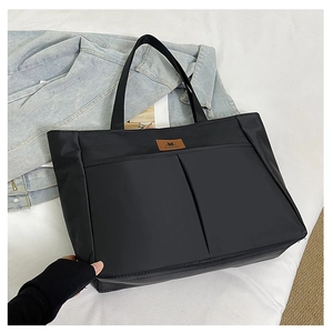 Close-up of black nylon tote bag with front pocket and leather label for daily commute