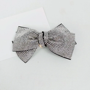 Close-up of a sparkling silver rhinestone bow hair clip on a sleek black base