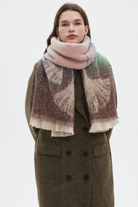 Close-up of gradient knit scarf with fringe detail on a dark olive wool coat
