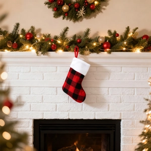 Detail of red and black buffalo plaid Christmas stocking with white plush trim on fireplace