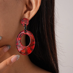 Detail of red marble texture acrylic round earrings worn by model for elegant style