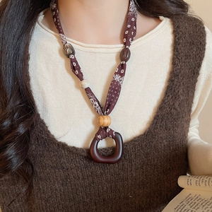 Detailed shot of ethnic necklace with printed fabric, wooden beads and acrylic ring charm