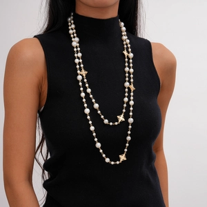 Détail d'un collier de perles multicouche avec des breloques de croix vintage dorées