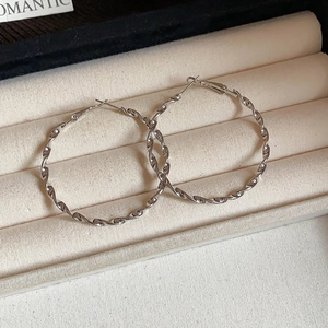 Detail of silver twisted hoop earrings featuring spiral texture on soft velvet display