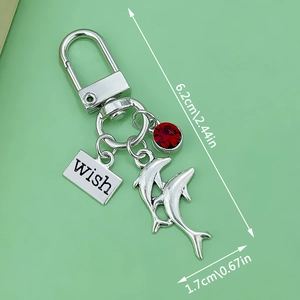 Blue resin dolphin keychain with silver wish tag and red gemstone charm detail