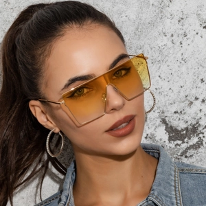 Oversized square sunglasses with gradient orange lenses and gold metal frame on a model
