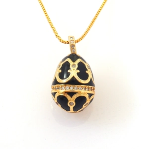 Detail of egg pendant necklace featuring black enamel with golden heart patterns
