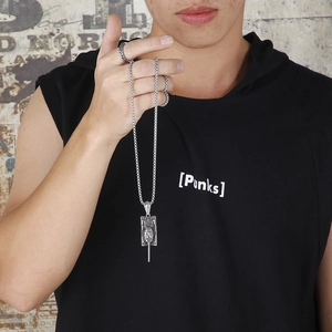 Close-up of a silver vintage tank pendant on a metal chain worn by a street style model