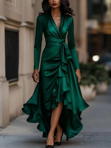 Deep V-neck emerald satin dress with ruffled hem and waist tie shown in city night