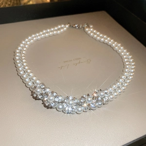 Detail view of double-layer pearl necklace with sparkling rhinestone flowers in a gift box