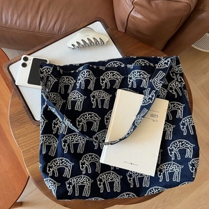 Detail of navy blue canvas tote bag with white sheep print on a wooden table