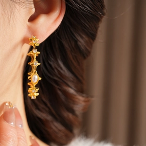 Macro shot of gold-plated hoop earrings featuring vintage pearls and sparkling zircon accents