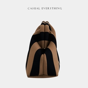 Close-up of brown and black striped knitted cloud bag with a woven texture finish