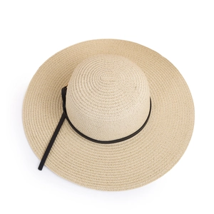 Macro shot of fine beige straw weave texture and black leather strap on sun hat