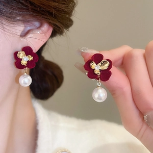 Detail of red flocked flower earrings with pearl pendant on model's ear for autumn style