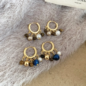 Detailed close-up of 18k gold plated hoop earrings with tiger eye and pearl bead tassels