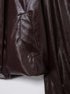 Detail of burgundy faux leather jacket showing stitching on pocket and smooth texture