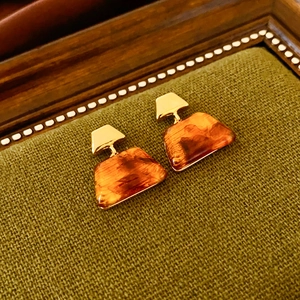 Macro shot of vintage resin trapezoid earrings with gold plating on green fabric