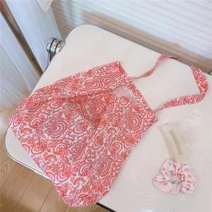 Detail view of cotton shoulder bag with vintage floral paisley print and matching hair tie