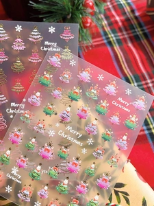 Macro shot of gold Christmas tree nail stickers with Merry Christmas text on plaid backdrop