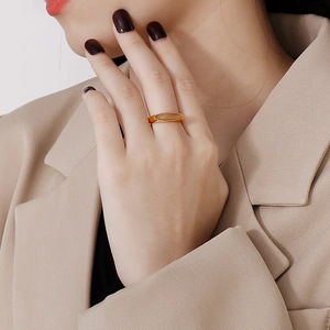 Detail shot of a model wearing a gold ring with a large oval brown gemstone in warm tones