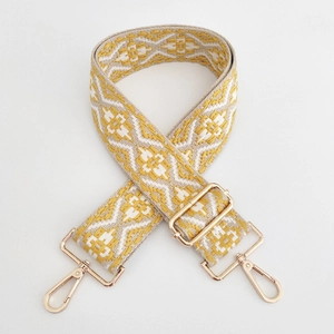 Close-up of ethnic jacquard purse strap with yellow geometric patterns and gold metal hooks