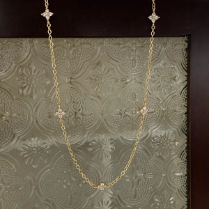 Detailed view of the gold chain necklace featuring five sparkling clover leaf pendants