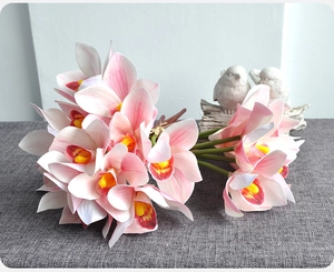 Detail of 3D printed pink cymbidium orchids with yellow accents on a gray textured surface