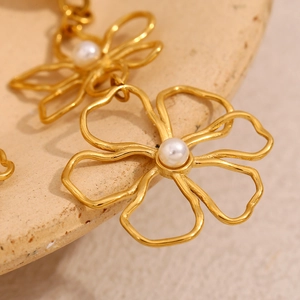 Macro shot of 18K gold plated wire flower stud earrings with a central white pearl inlay