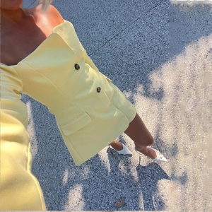 Detail of yellow off-shoulder long sleeve double-breasted dress with black buttons