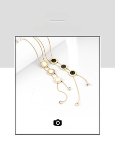 Detail of gold double tassels necklaces with Roman numerals and black white pendants